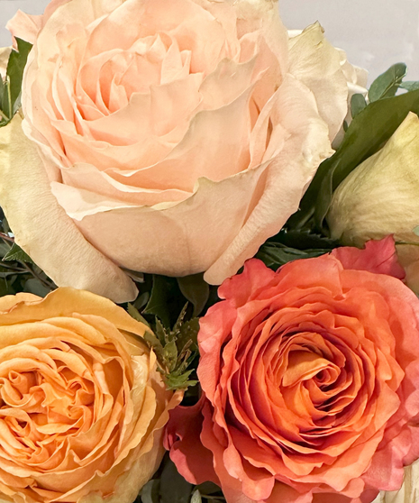 One dozen red roses with lilies and fancy greenery in an elegant, tall vase