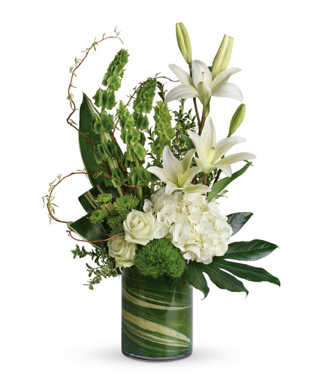 High style vase with leaf swirl and beautifulwhite flowers of roses, hydrangeaand lilies accented with bells of ireland