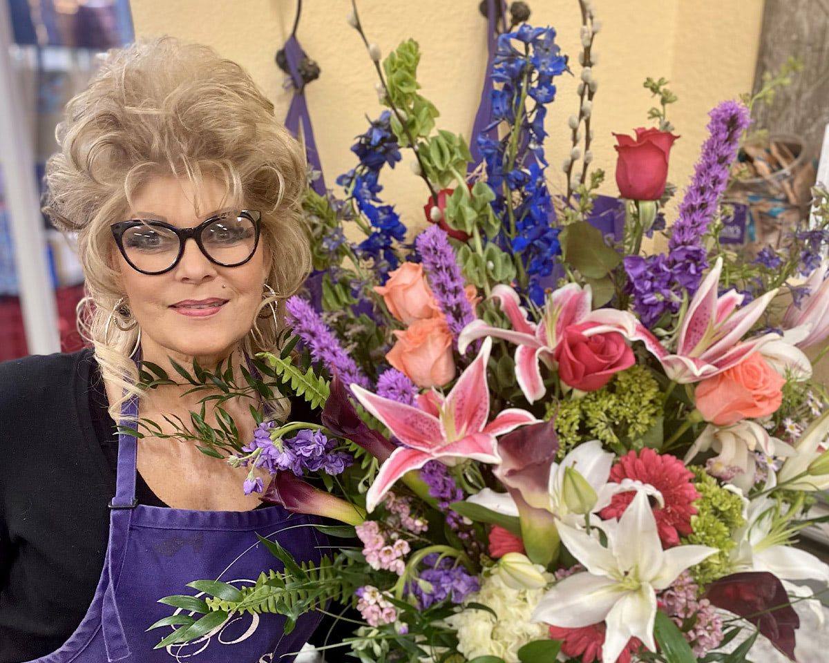 A Bagoy's floral designer poses, proudly, with one of her bouquets